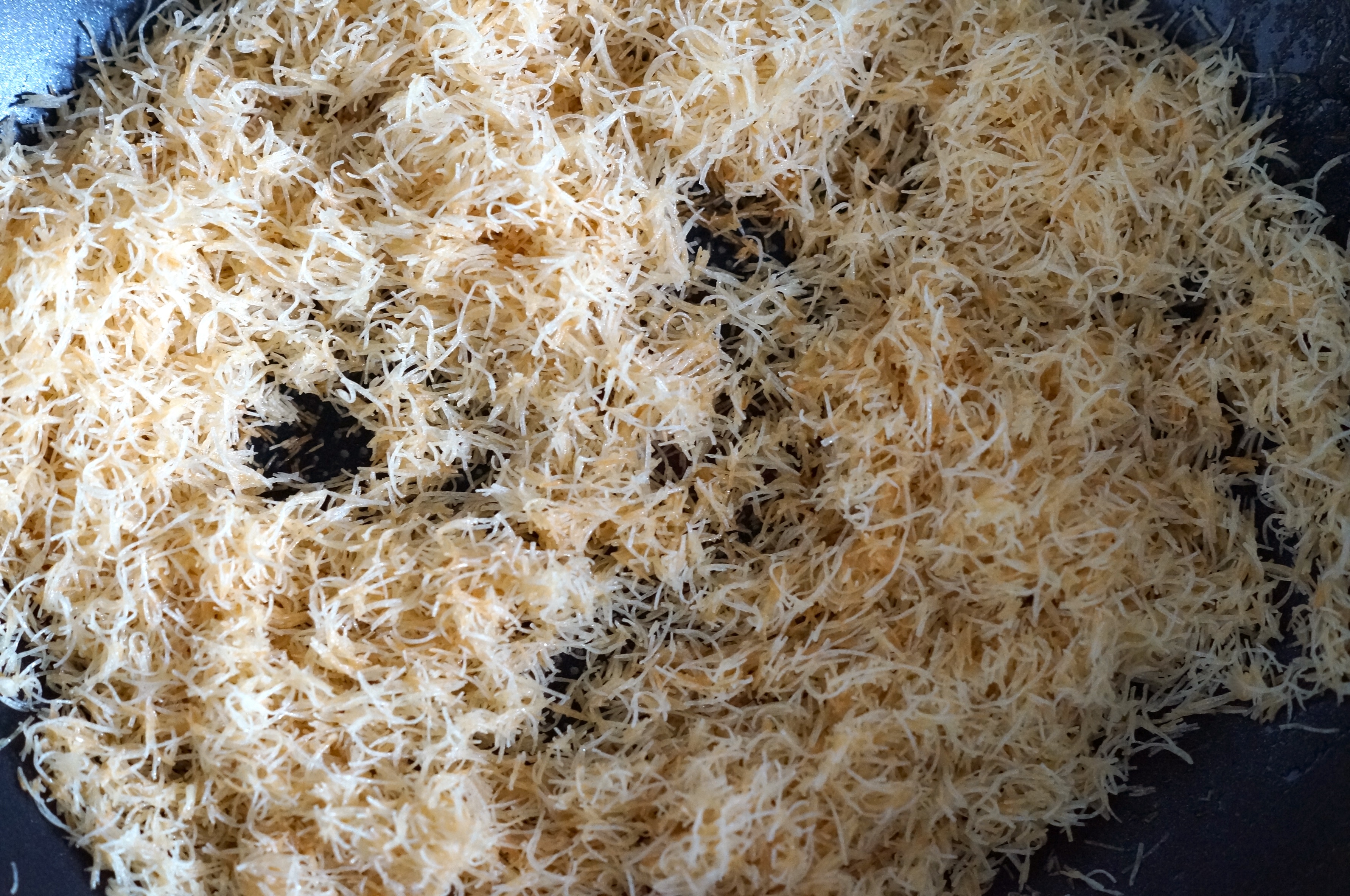Kataifi pastry being toasted in a pan until golden and crispy